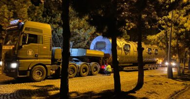 Ładunek ponadgabarytowy umieszczony na lawecie niskopodwoziowej przygotowany do transportu. Na drodze w nocy między drzewami.