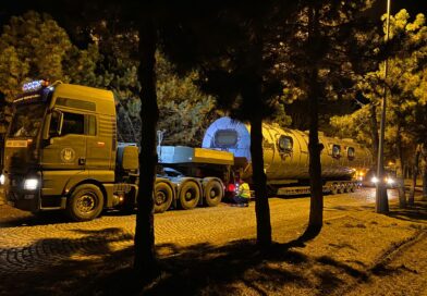 Ładunek ponadgabarytowy umieszczony na lawecie niskopodwoziowej przygotowany do transportu. Na drodze w nocy między drzewami.